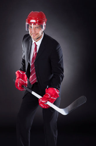 a photo of a man in a suite with a red helmet and a hockey stick
